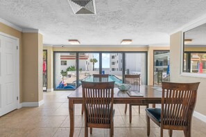 Un espace repas avec vue sur la piscine, des chaises en bois et une table en verre.