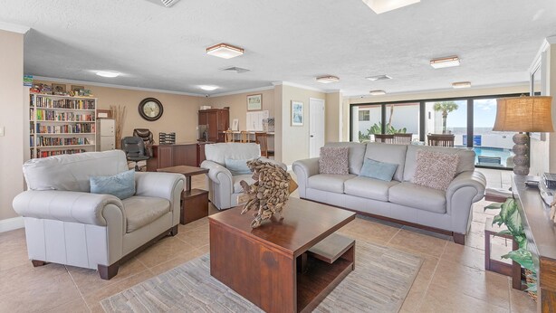 A spacious living room with two sofas, a coffee table, and a bookshelf. - Las Brisas 502 (New Smyrna Beach)