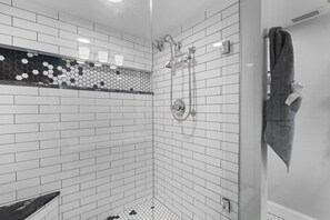 Une douche d’angle avec des carreaux de métro blancs et un motif de mosaïque hexagonale sur le bas du mur.