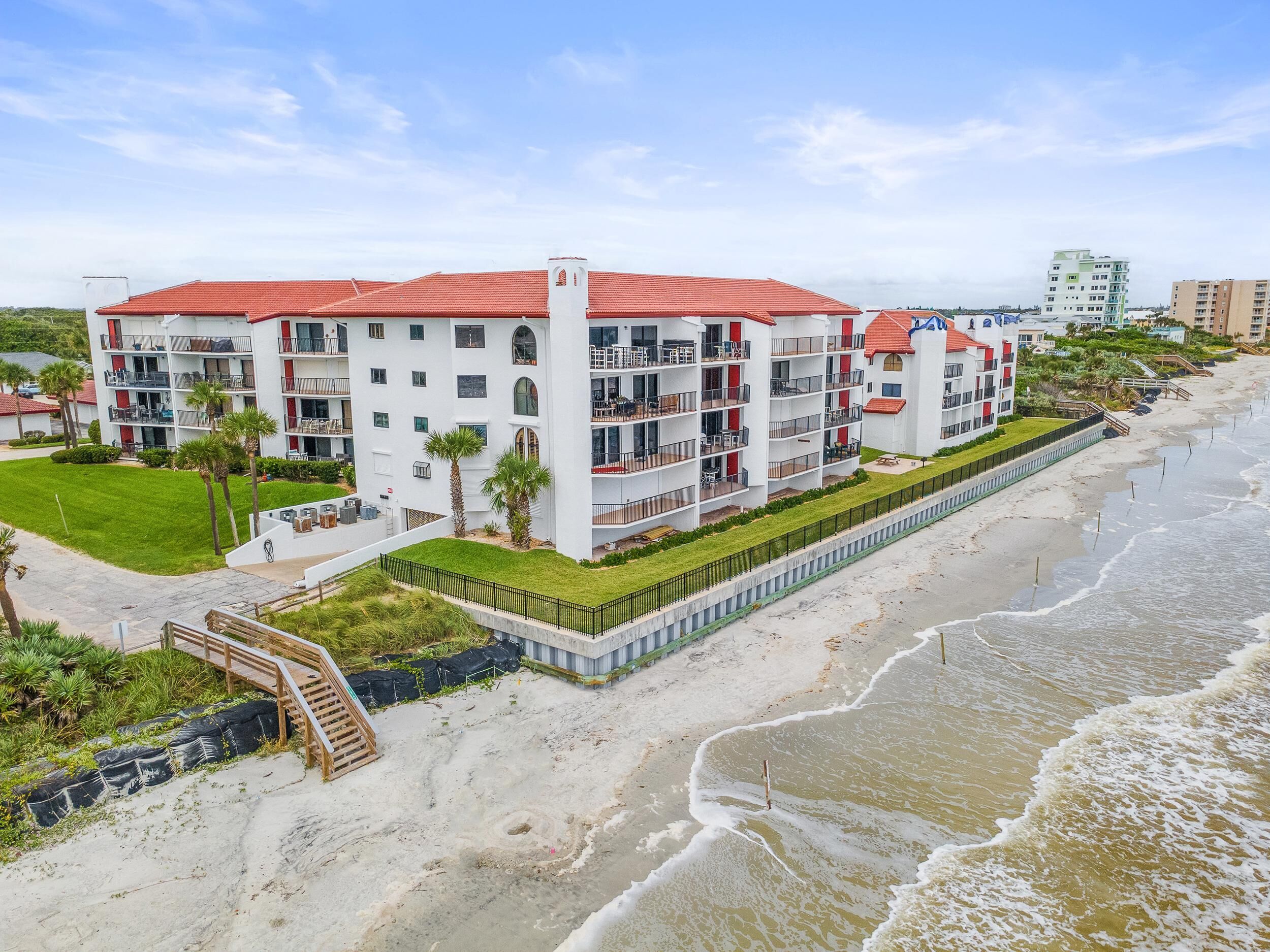 Un hôtel à plusieurs étages doté de balcons, offrant une vue sur la plage et comprenant un jardin aménagé.