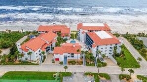 A coastal hotel with multiple buildings, a swimming pool, and a beach view. - Las Brisas 502 (New Smyrna Beach)