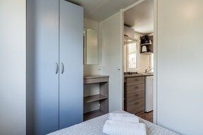 Una camera da letto con un letto, un armadio, un bagno con uno specchio e un angolo cottura.