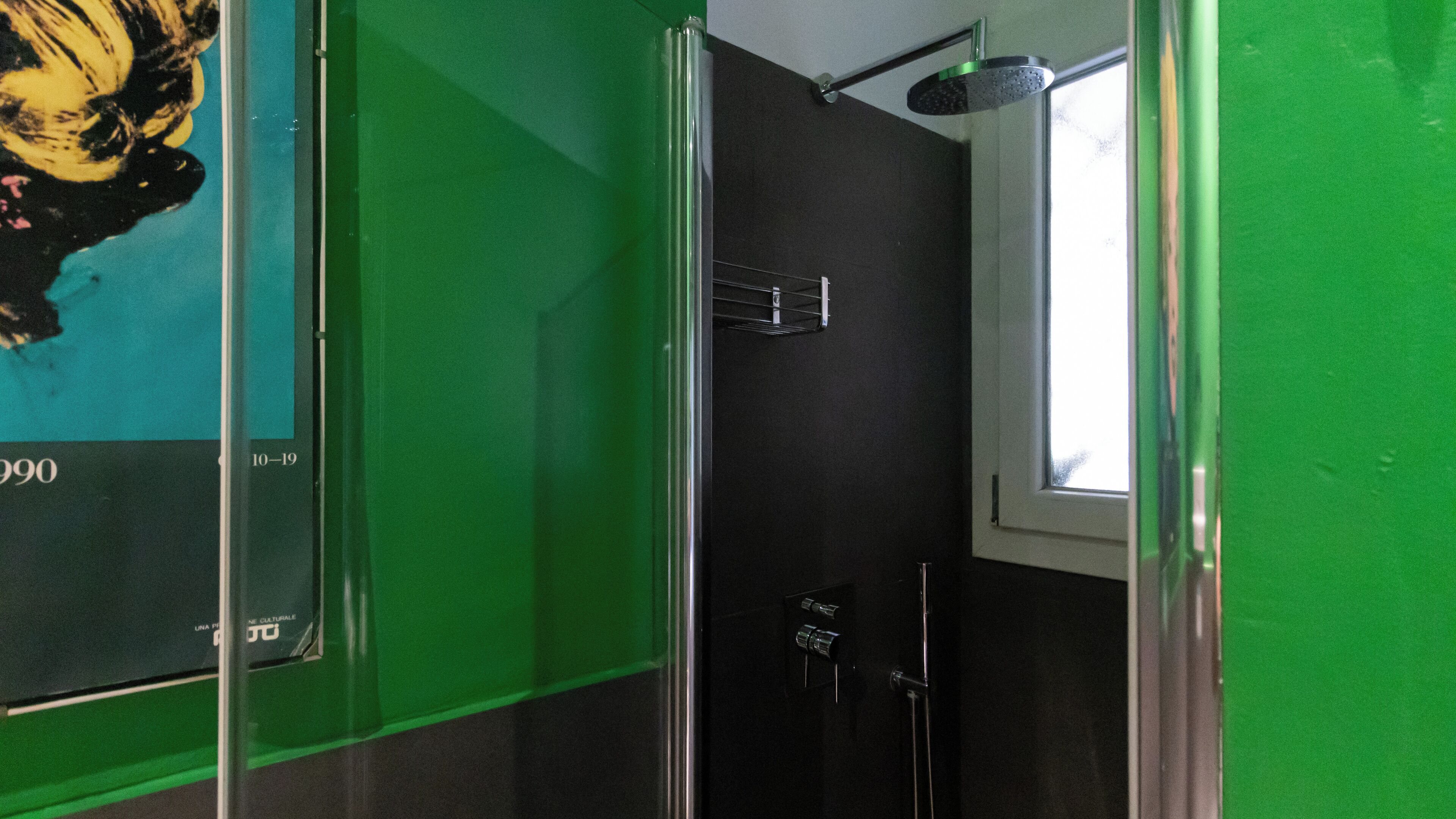 Une salle de bain avec une douche, une fenêtre et un mur vert.