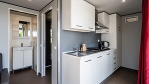 A compact kitchen with white cabinets, a stove, and a coffee maker.