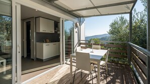 A modern kitchen with white cabinets and a dining area with a table and chairs. - Mobile Home 'Camping Belsito Venere 515' with Shared Pool, Wi-Fi and Air Conditioning (Vico)