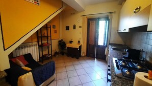A compact kitchen with a stove, a dining area with a table and chairs, a sofa, and a staircase leading to an upper level. - N. & A. Sweet Home, 5 minutes from the city center of Lucca (Lucca)