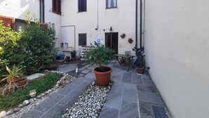 A courtyard with a stone pathway, potted plants, and a small table with chairs. - N. & A. Sweet Home, 5 minutes from the city center of Lucca (Lucca)
