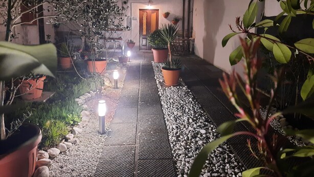 A pathway lined with potted plants and small lights leading to a building entrance. - N. & A. Sweet Home, 5 minutes from the city center of Lucca (Lucca)