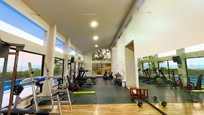 A gym with exercise equipment, large windows, and a wooden floor. - Brand New lake view Penthouse with A/C, pool, gym, tennis in common area (Río Oro)