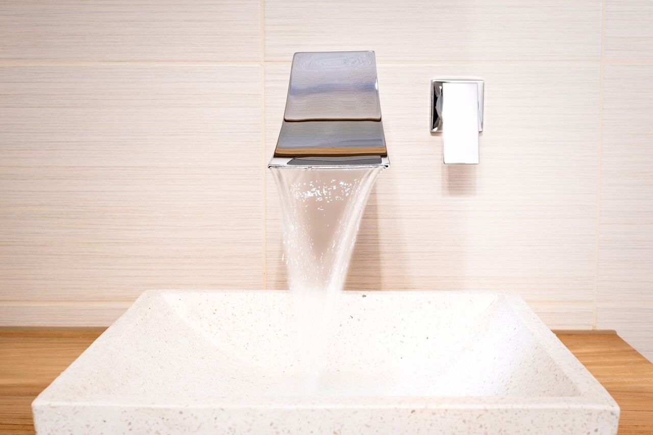 Une salle de bain moderne avec un lavabo carré, un robinet chromé et un interrupteur fixé au mur.
