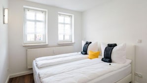 A bedroom with two beds, white bedding, a yellow pillow, and a black pillow. - High-quality, centrally located apartment in the middle of the city (Rudolstadt)