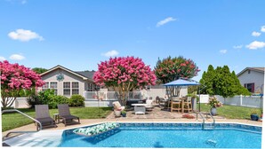 Un jardin avec une piscine, des meubles de patio et un belvédère.