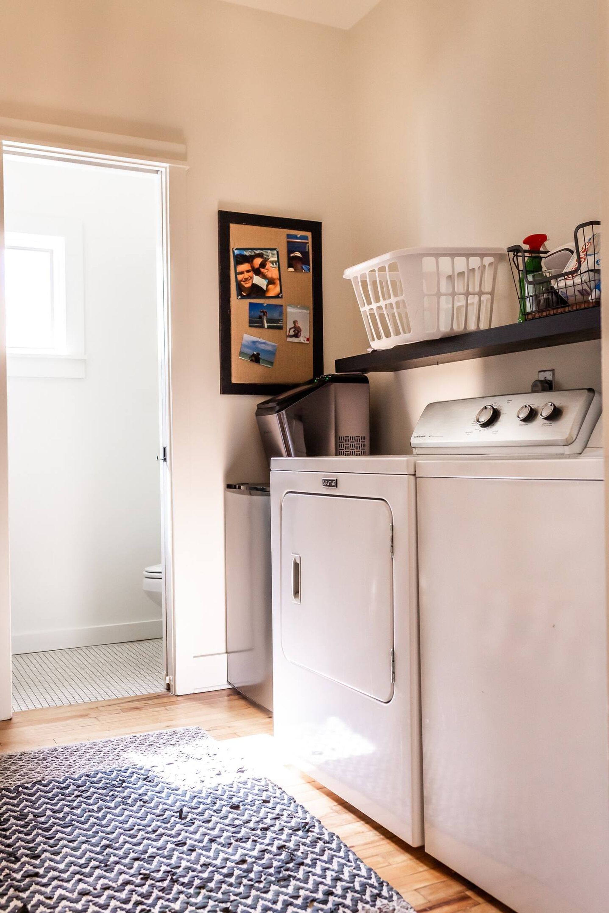 A laundry area with a washing machine, dryer, and a basket on a shelf.