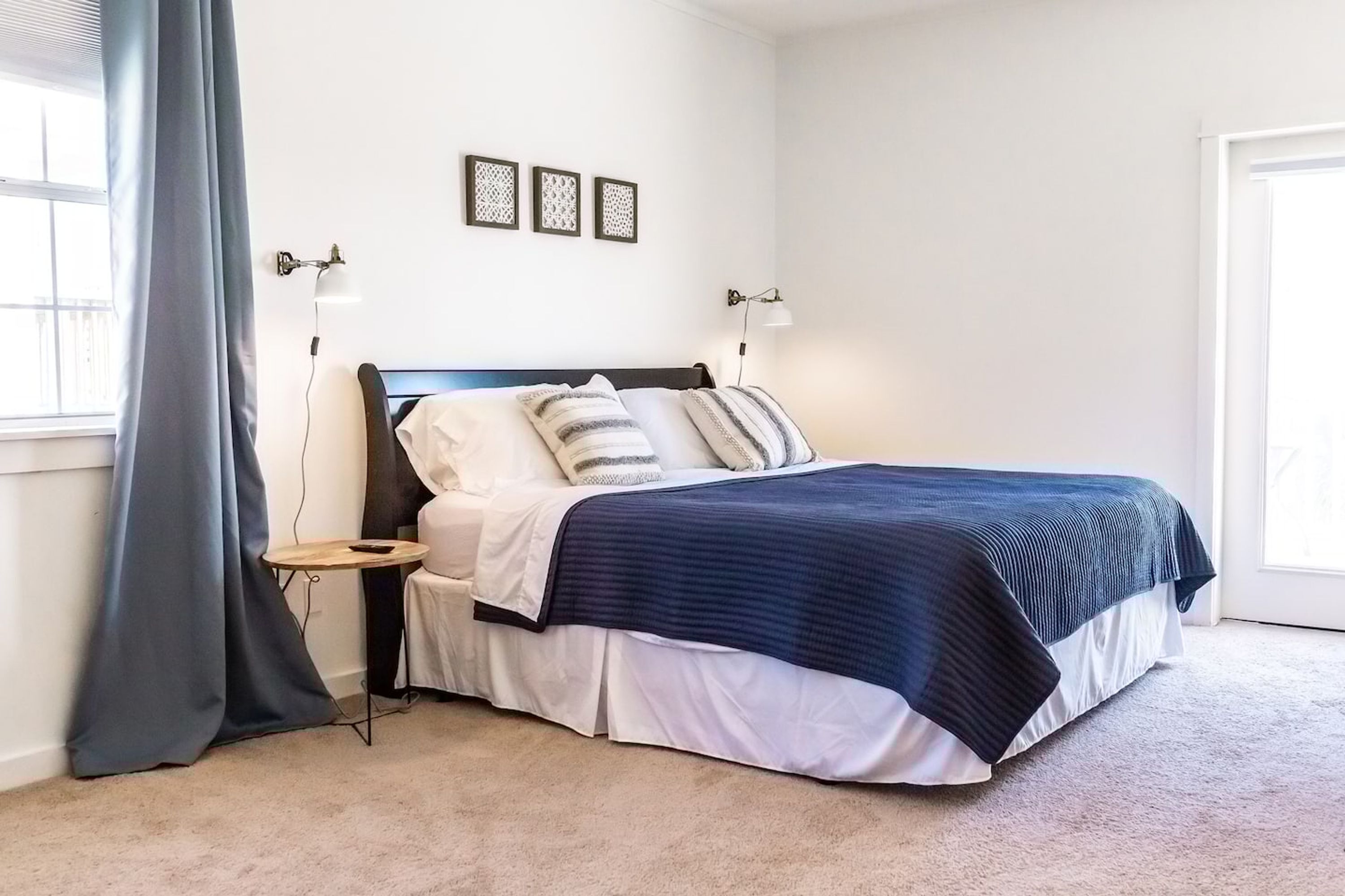 Een slaapkamer met een bed, nachtkastjes, een raam met gordijnen en wandlampen.