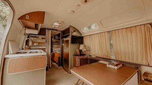 A compact RV interior with a kitchenette, a dining area, and a small seating space. - Boho Blue & Airstream Nearby all Things Memphis (Memphis)