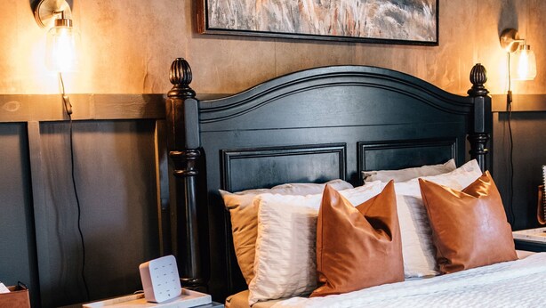 A bedroom with a dark wood headboard, a patterned rug, and a painting on the wall. - Moody Blues Studio Perfect for Work or Romance (Memphis)