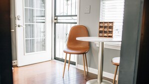 A room with a wooden floor, a brown chair, a white table, and a window with blinds. - Moody Blues Studio Perfect for Work or Romance (Memphis)
