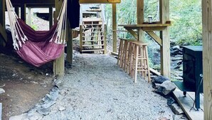 A rustic wooden structure with a hammock, a ladder, and a bar stool area. - Slate Crossing Creekside Dome (Cosby)