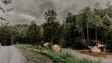 A rural road with a campsite featuring tents and a small wooden structure.