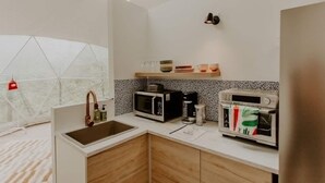 A compact kitchen with a sink, microwave, and toaster, and a window with a view of trees. - Whispering Waters Dome Getaway (Cosby)