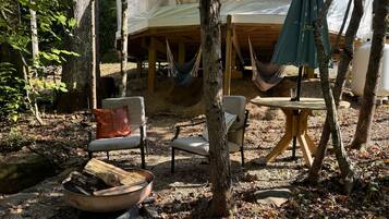 A rustic outdoor seating area with a hammock, a table, and chairs.