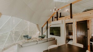 A modern interior with a dining area, a sofa, and a staircase. - Moonshine Hollow Dome by Rafting (Cosby)
