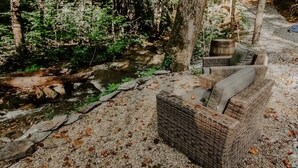 A wicker sofa with cushions near a forest stream. - Moonshine Hollow Dome by Rafting (Cosby)