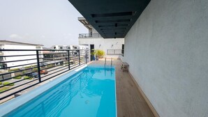 Une piscine sur le toit, dotée d’une terrasse en bois et d’une rambarde en métal.