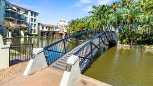 Un puente sobre un canal, con edificios y palmeras al fondo.