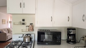A kitchen with a gas stove, a microwave, and a coffee maker. - Sweetgum Hideaway Home (Athens)
