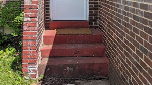 A house with a white front door, a brick exterior, and a small porch with steps leading to the door. - Sweetgum Hideaway Home (Athens)