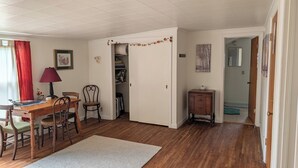 A room with a wooden desk, chairs, a lamp, a door leading to a closet, and a small cabinet. - Sweetgum Hideaway Home (Athens)