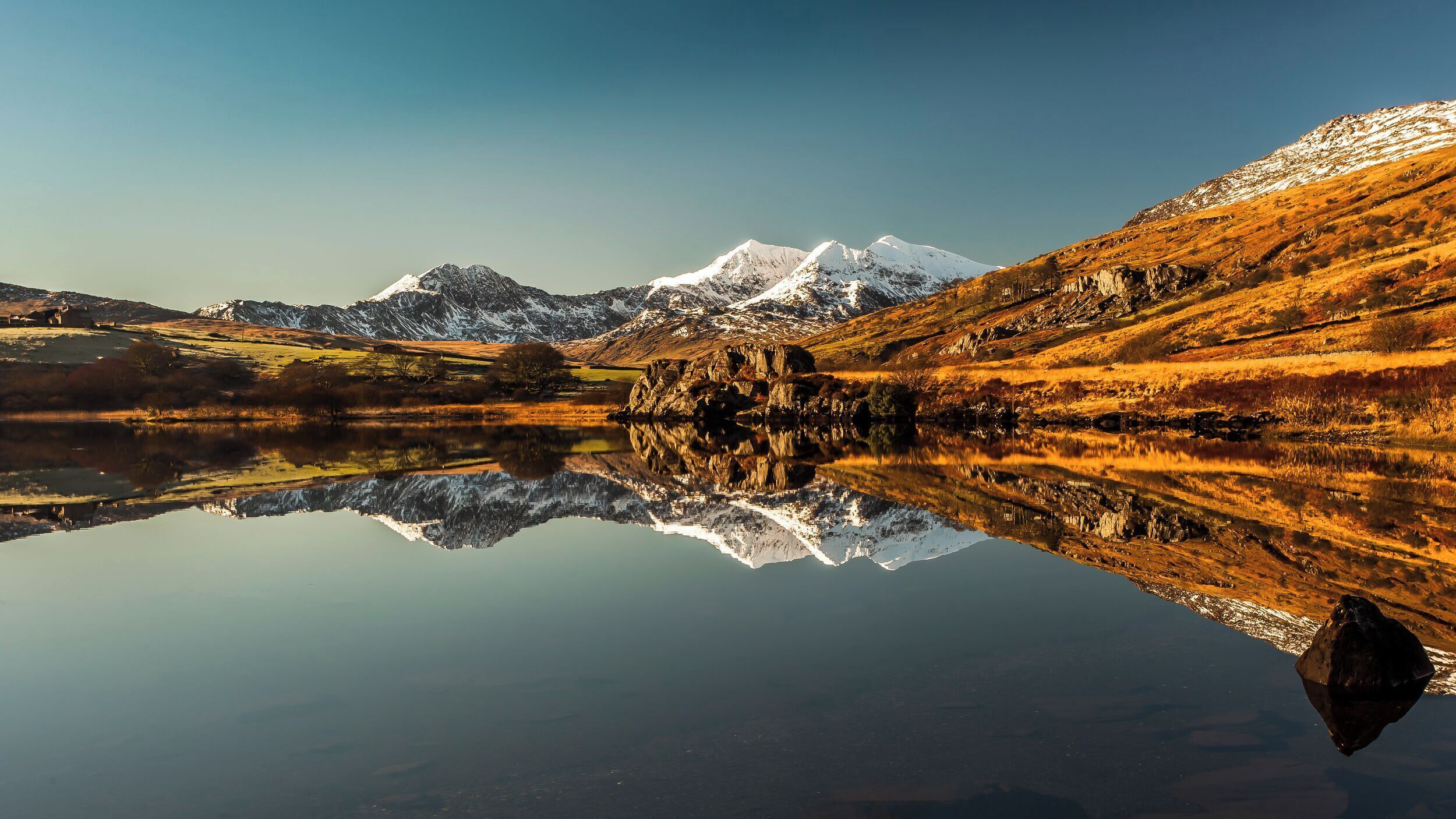 Un lac paisible qui reflète un paysage montagneux sous un ciel dégagé.