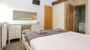 Ein Schlafzimmer mit Bett, Schreibtisch, Spiegel und einem Holzbalken an der Decke.