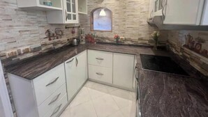 A kitchen with white cabinets, a dark countertop, and a stone backsplash.