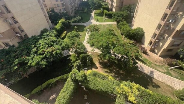 A residential area with high-rise buildings, a central green space, and a small water feature.