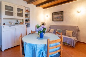 A dining area with a round table, chairs, a cabinet, and a sofa.
