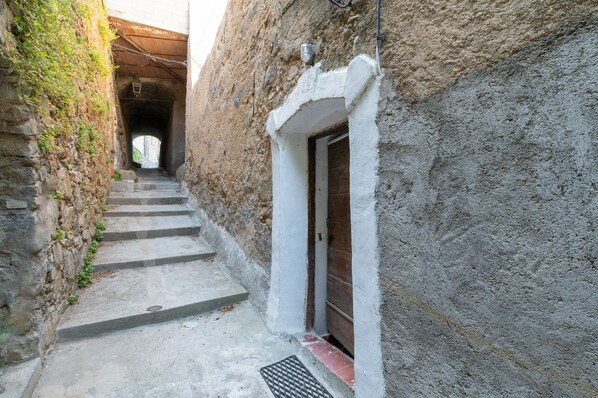 A narrow stone staircase leading to a door, with a metal grate at the bottom.