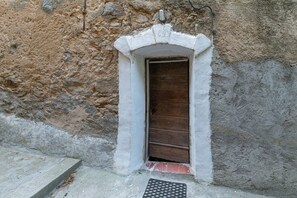 A stone wall with a wooden door and a small step leading to a door mat.