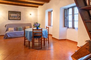 A dining area with a table set for two, a sofa in the background, and a staircase leading to an upper level.