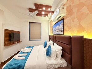 A modern hotel room with a bed, a flat-screen TV, a ceiling fan, and an air conditioning unit. - Rasa Boutique Stay (Greater Noida)