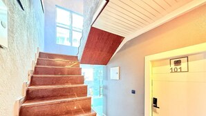 A staircase with a wooden finish leading to a door marked with the number 101. - Rasa Boutique Stay (Greater Noida)