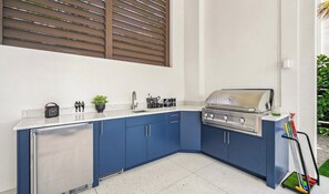 A compact kitchen with a built-in grill, a refrigerator, and a sink.