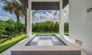 A hot tub with a view of a landscaped garden and palm trees.