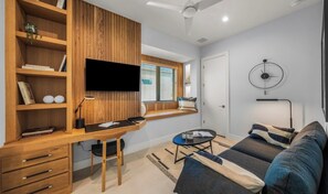 Ein modernes Wohnzimmer mit einem Holzeinbauschreibtisch, einem Flachbildfernseher, einer Couch und einem Couchtisch.