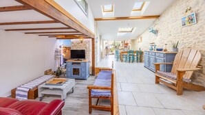 A spacious living area with a sofa, wooden chairs, a TV, and a dining area with a table and chairs.