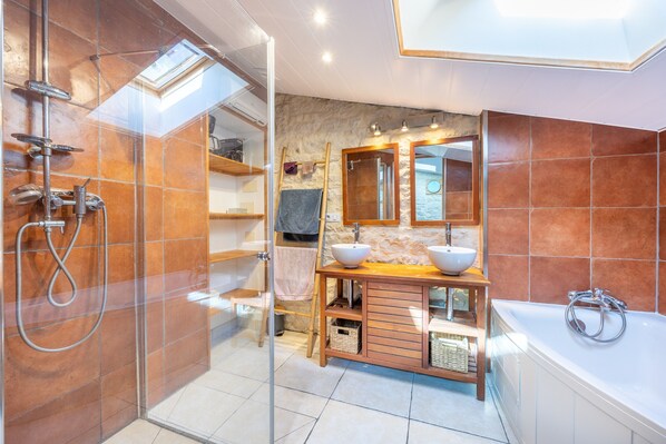 A bathroom with a glass shower enclosure, a wooden vanity with a sink, and a bathtub.