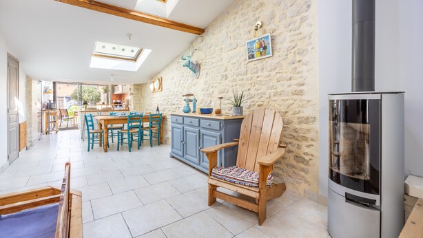 A spacious kitchen with a stone wall, wooden ceiling beams, and a built-in stove.