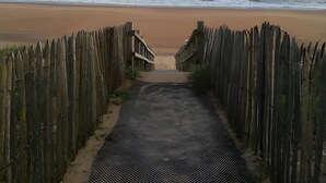 A beach pathway leading to the shore, flanked by wooden fences.