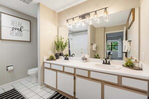 A modern bathroom with a double sink vanity, a large mirror, and a 'RELAX SOAK REWIND' sign. - Coffman Escape Stay for 6 (Branson)
